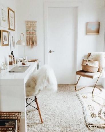 Biuro domowe w jasnych odcieniach, biały polerowany stół, makrama, mały dywanik, elementy z wikliny