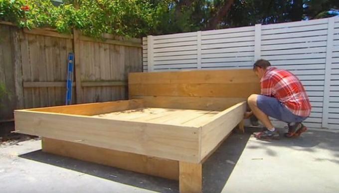 Człowiek buduje łóżko w środku podwórza.